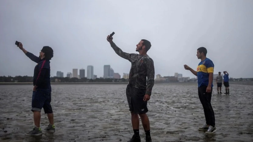 Varias personas se hacen selfies en la costa con el mar retirado