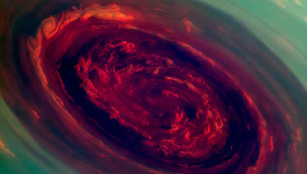 Esta imagen a falso color muestra el increíble ojo del vórtice que corona el polo norte de Saturno. El rojo tiñe las nubes más bajas y los tonos verdes las más altas. Aún no se sabe por qué gira este enorme huracán, de unos 4.000 kilómetros de ancho. 