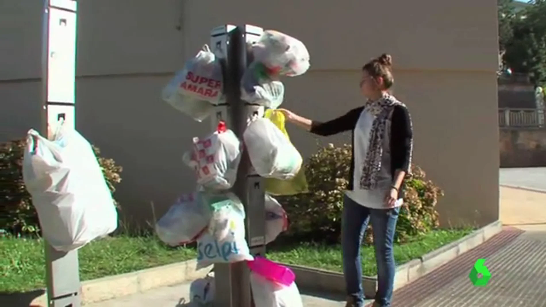Una mujer coloca una bolsa de basura en una columna de reciclaje