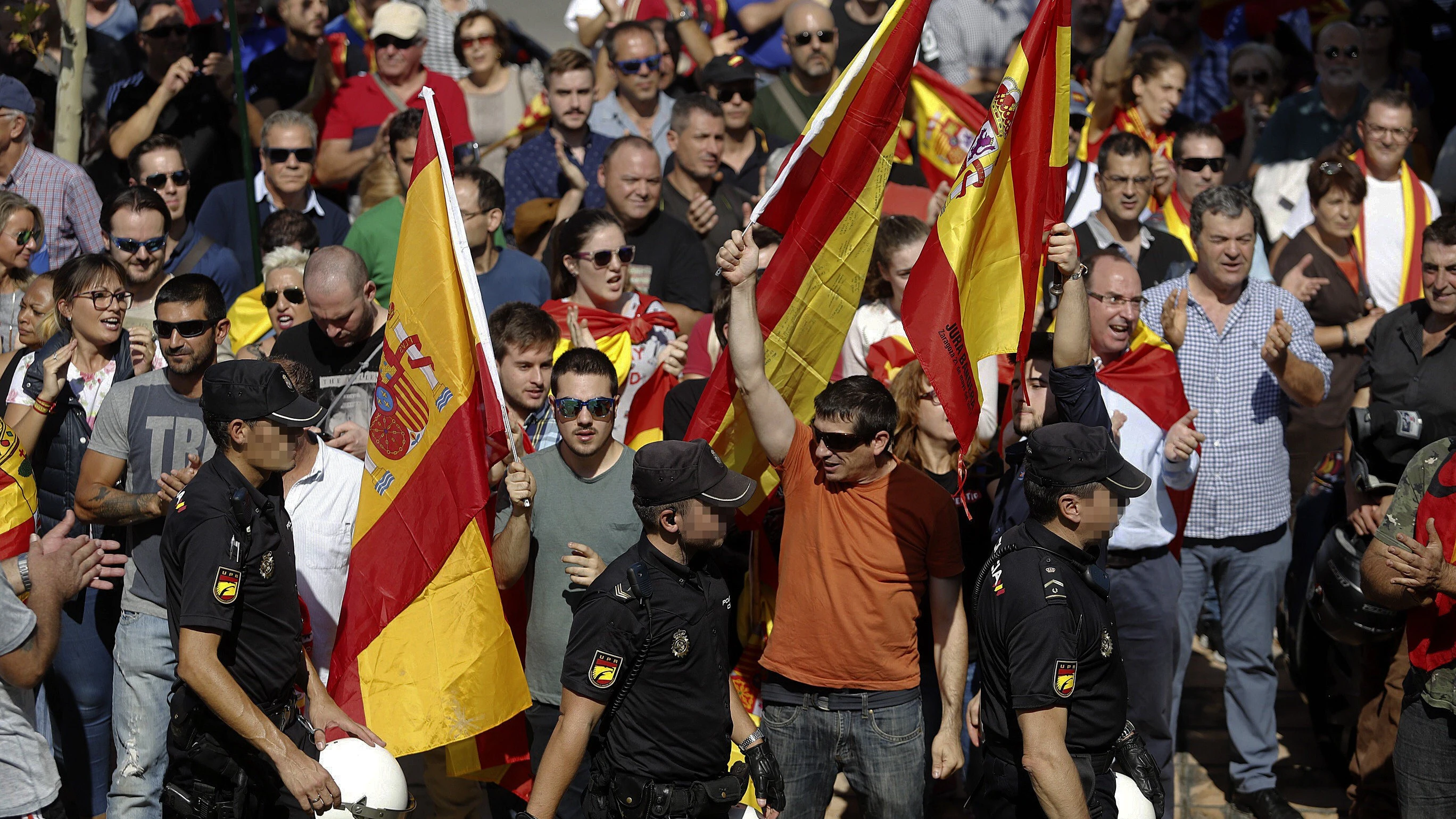 Un grupo de personas, con banderas españolas, aplaude a los agentes de la Policía Nacional en la entrada al pabellón Siglo XXI de Zaragoza