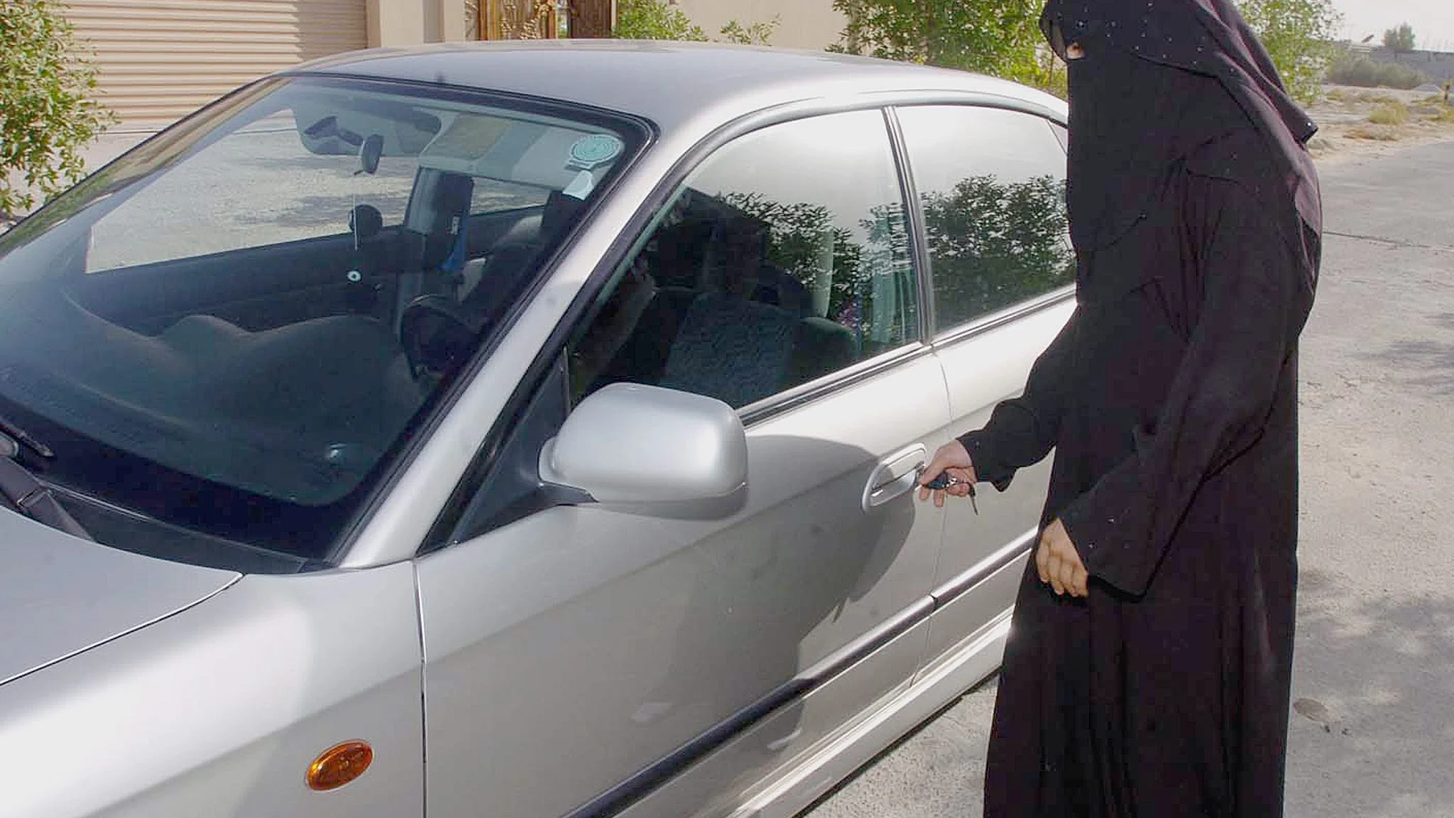 Una mujer saudí abre la puerta de un coche familiar en Riad, Arabia Saudi.