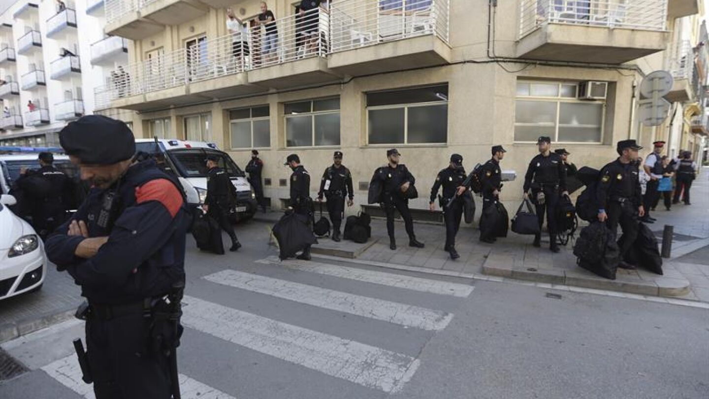 Un grupo de polic&iacute;as nacionales espera su transporte delante del hotel Mont-Palau de Pineda