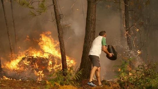 Una persona arroja agua en el incendio en la zona de Zamanes, Vigo Una persona arroja agua en el incendio en la zona de Zamanes, Vigo
