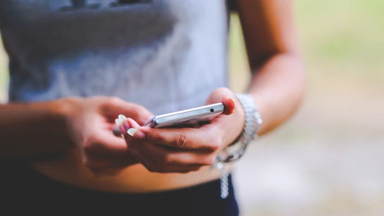 Una persona con un teléfono móvil Una persona con un teléfono móvil