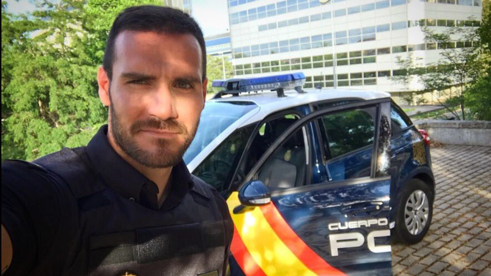 Saúl Craviotto posa con su uniforme de Policía al lado de un coche patrulla