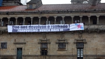 La portavoz del BNG en Bruselas, Ana Miranda, y el coordinador de Relaciones Internacionales, Rubén Cela, participan en un acto simbólico contra el expolio franquista en donde militantes colocaron un cartel en la fachada de la Catedral de Santiago