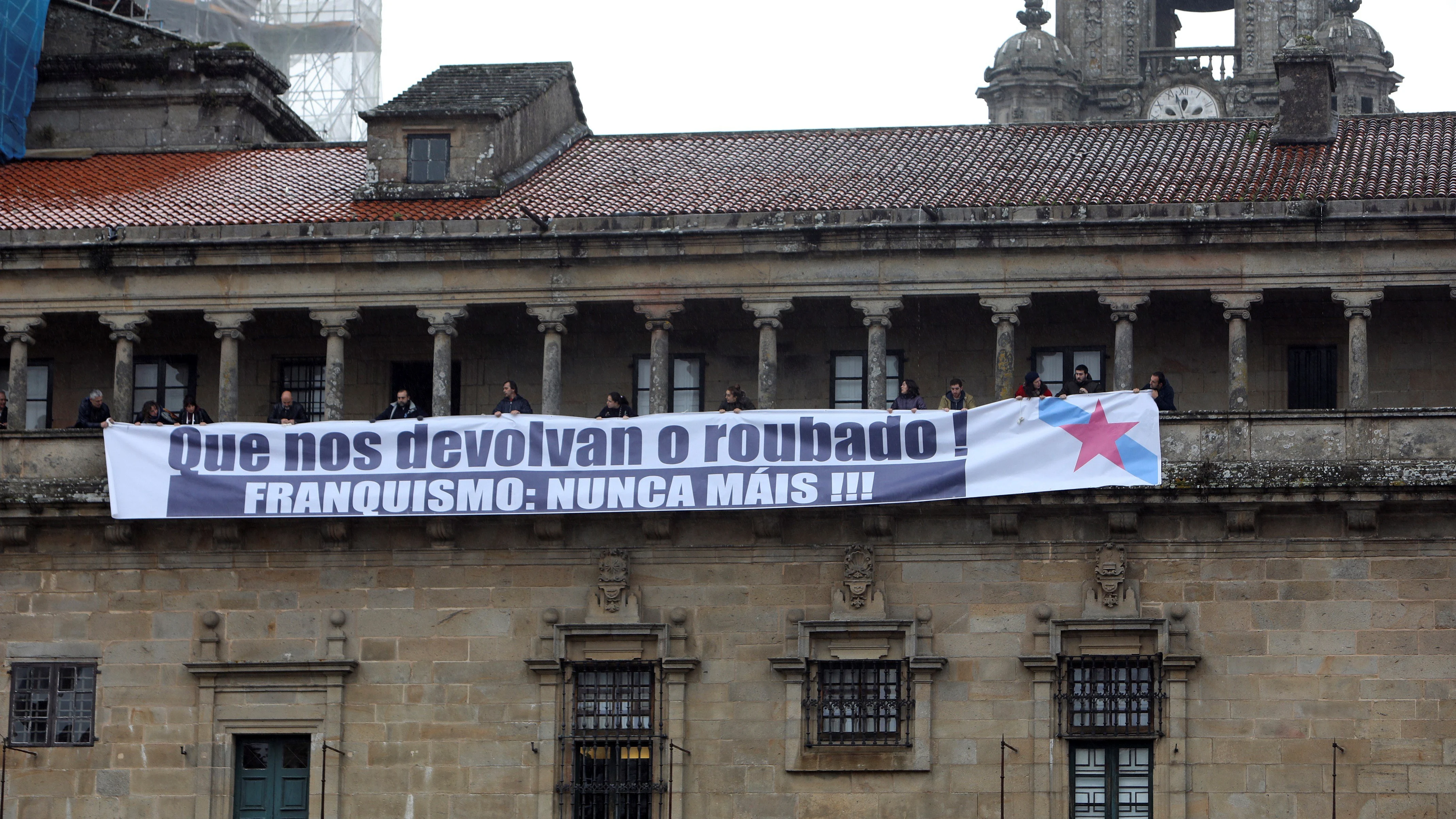 La portavoz del BNG en Bruselas, Ana Miranda, y el coordinador de Relaciones Internacionales, Rubén Cela, participan en un acto simbólico contra el expolio franquista en donde militantes colocaron un cartel en la fachada de la Catedral de Santiago