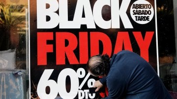 Un operario coloca un cartel en el escaprate de una tienda en la que anuncia grandes rebajas en el 'Black Friday'