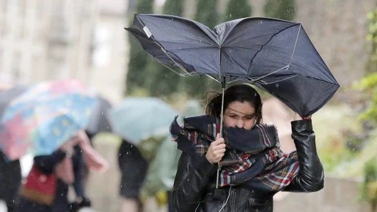 Una mujer combate los fuertes vientos y la lluvia Una mujer combate los fuertes vientos y la lluvia