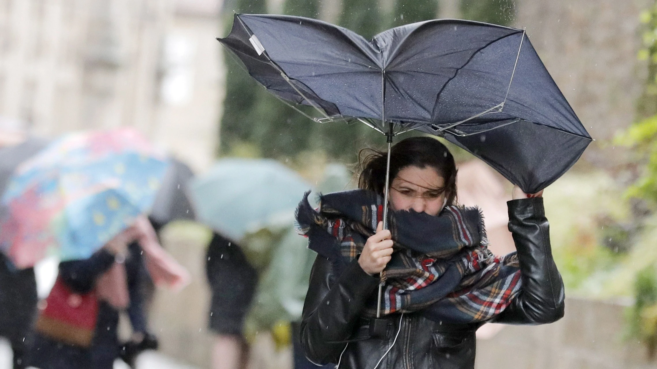 Una mujer combate los fuertes vientos y la lluvia