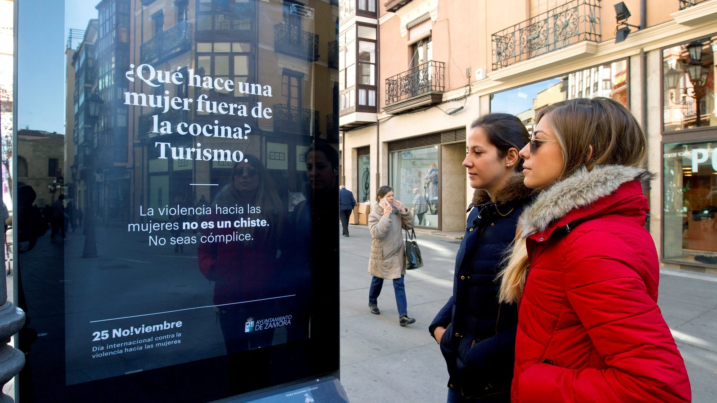 Dos mujeres observan uno de los carteles ubicados por las calles zamoranas de la campaña iniciada por el Ayuntamiento de Zamora