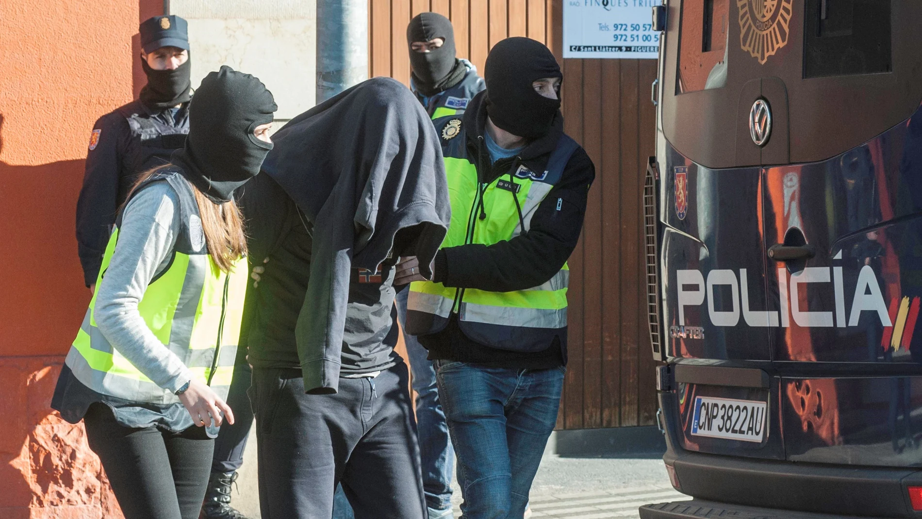 Agentes de la Policía Nacional acompañan a uno de los detenidos en Figueras, Gerona