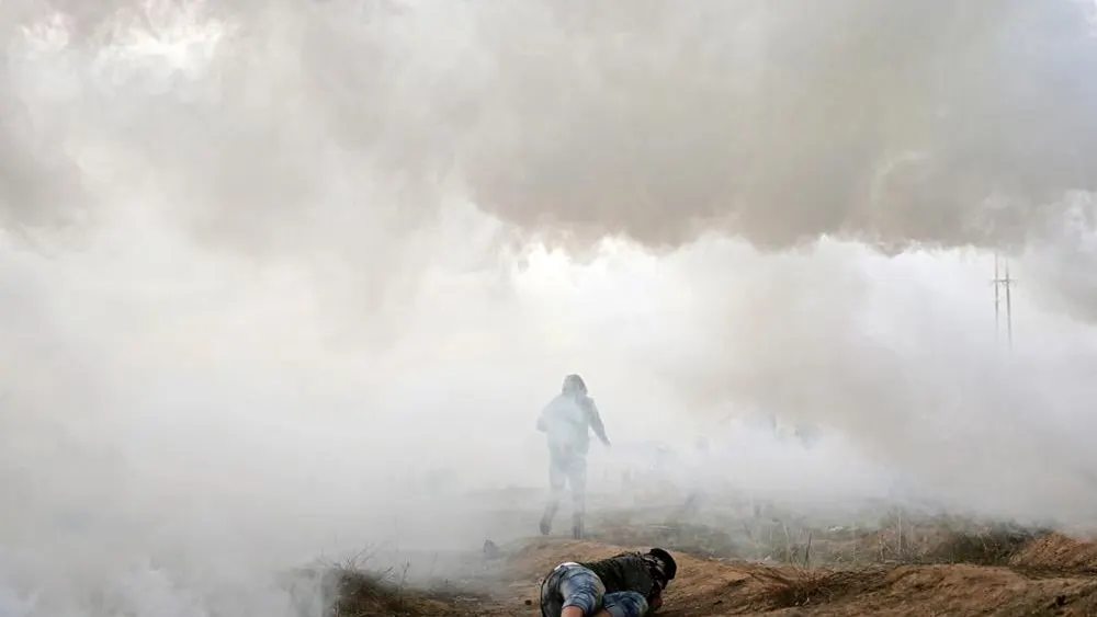 Manifestantes palestinos se cubren durante los enfrentamientos cerca de la frontera con Israel