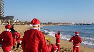 Personas disfrazadas de Papá Noel en tablas de pádel-surf