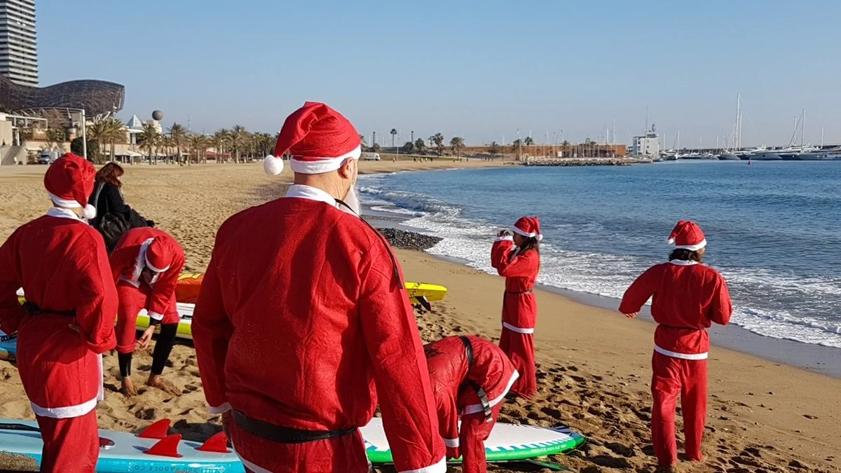 Personas disfrazadas de Papá Noel en tablas de pádel-surf