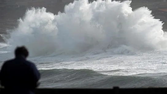 n hombre observa una ola romper en los acantilados cercanos a Suances n hombre observa una ola romper en los acantilados cercanos a Suances