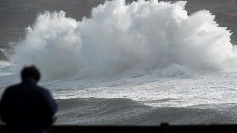 n hombre observa una ola romper en los acantilados cercanos a Suances