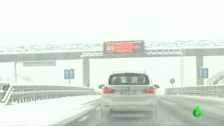 Un coche circula por una carretera cubierta de nieve