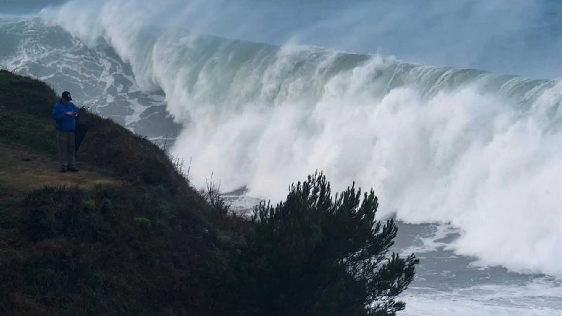 Un hombre fotografía las grandes olas que rompen ayer en la costa de la capital cántabra
