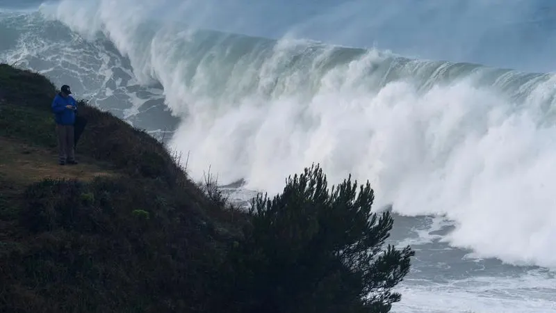 Un hombre fotografía las grandes olas que rompen ayer en la costa de la capital cántabra