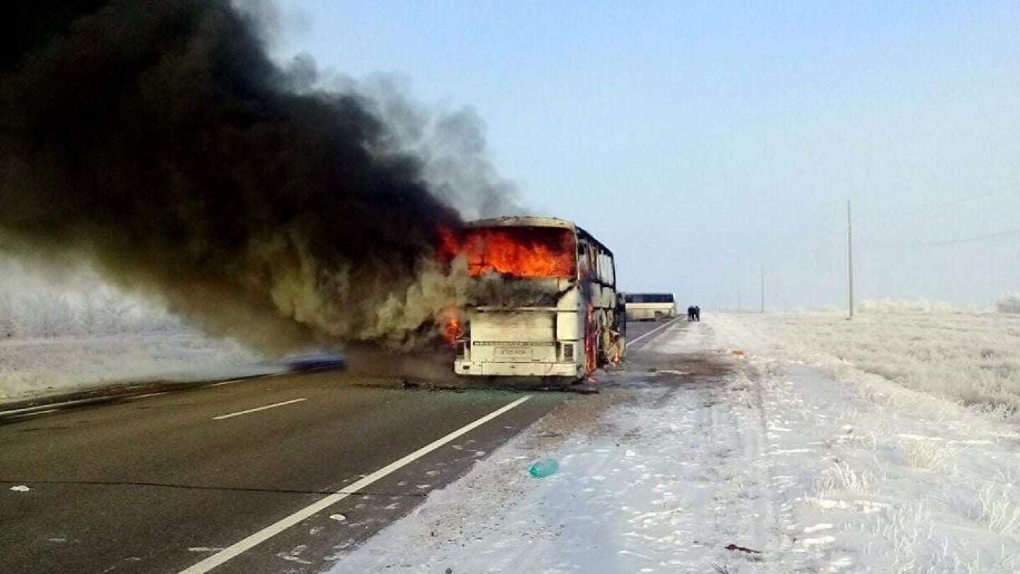 Una columna de humo se eleva desde un autob&uacute;s por una carretera en Kazajist&aacute;n
