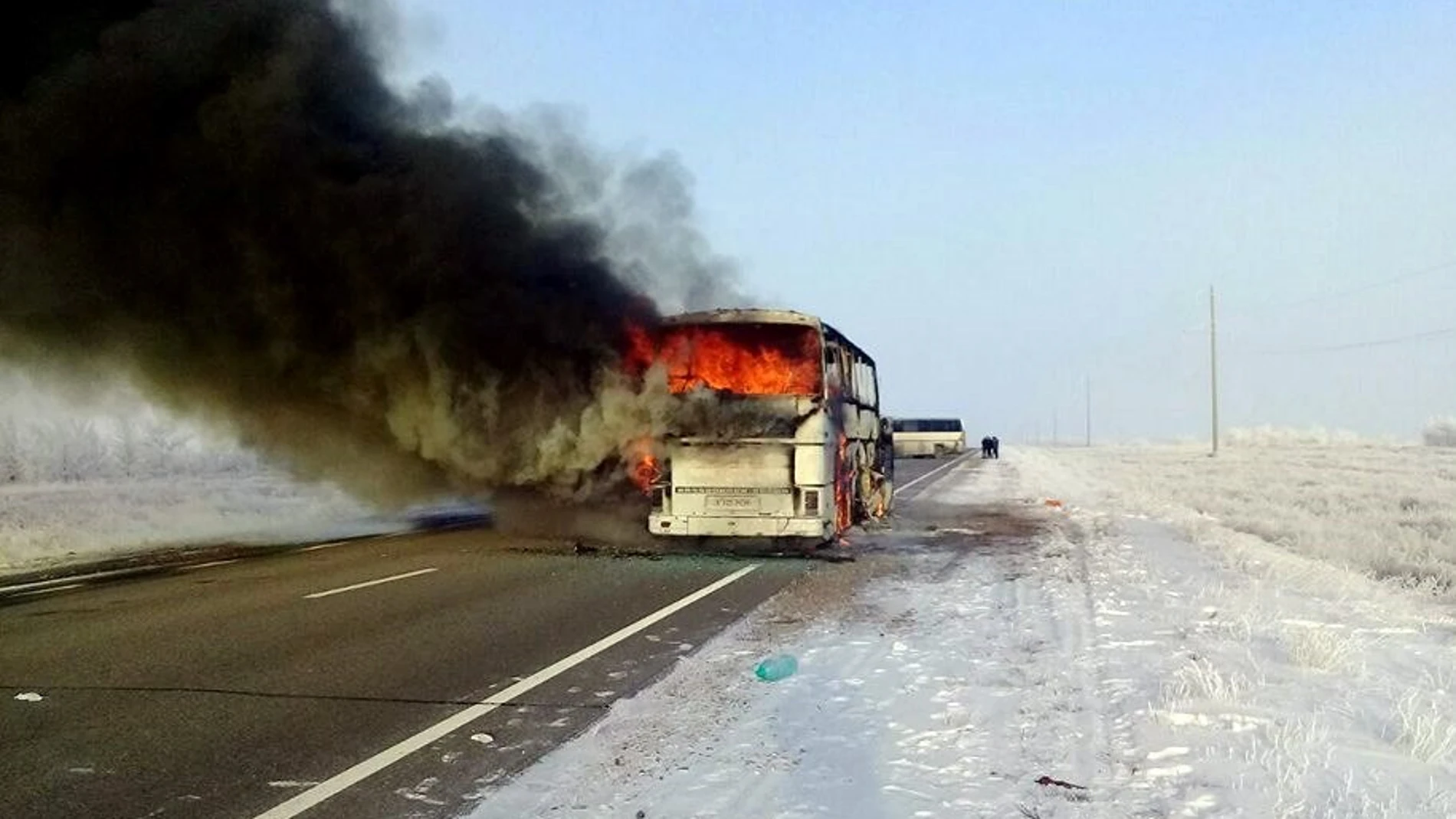 Una columna de humo se eleva desde un autobús por una carretera en Kazajistán