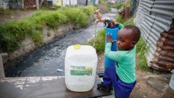 Un niño llenando una garrafa de agua en Ciudad del Cabo