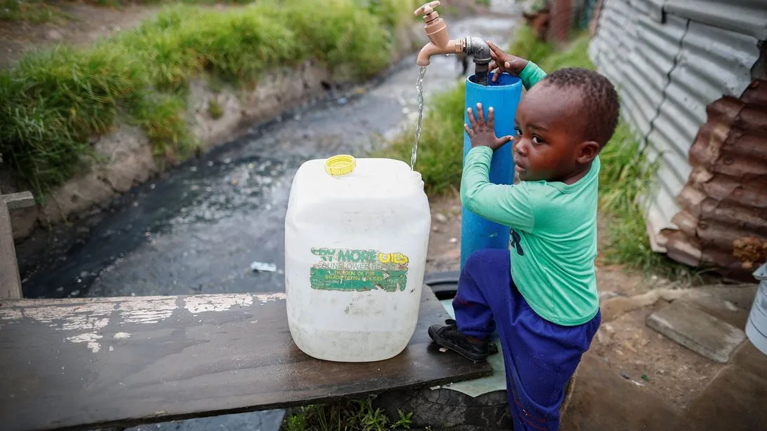 Un niño llenando una garrafa de agua en Ciudad del Cabo