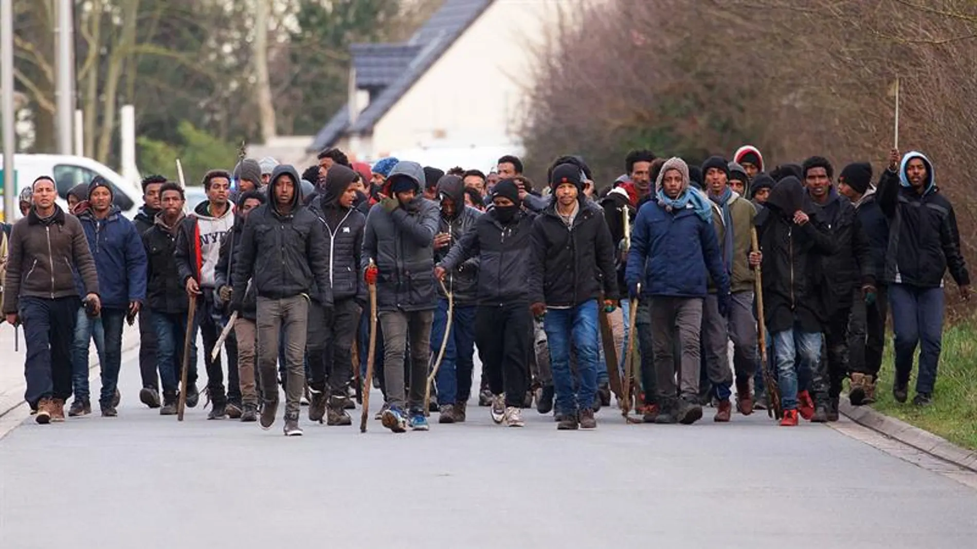 Un grupo de inmigrantes carga palos y piedras durante un enfrentamiento cerca del puerto de Calais