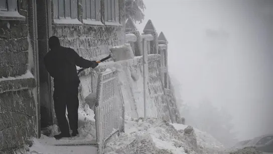 Un hombre retira la nieve de la puerta de una vivienda Un hombre retira la nieve de la puerta de una vivienda