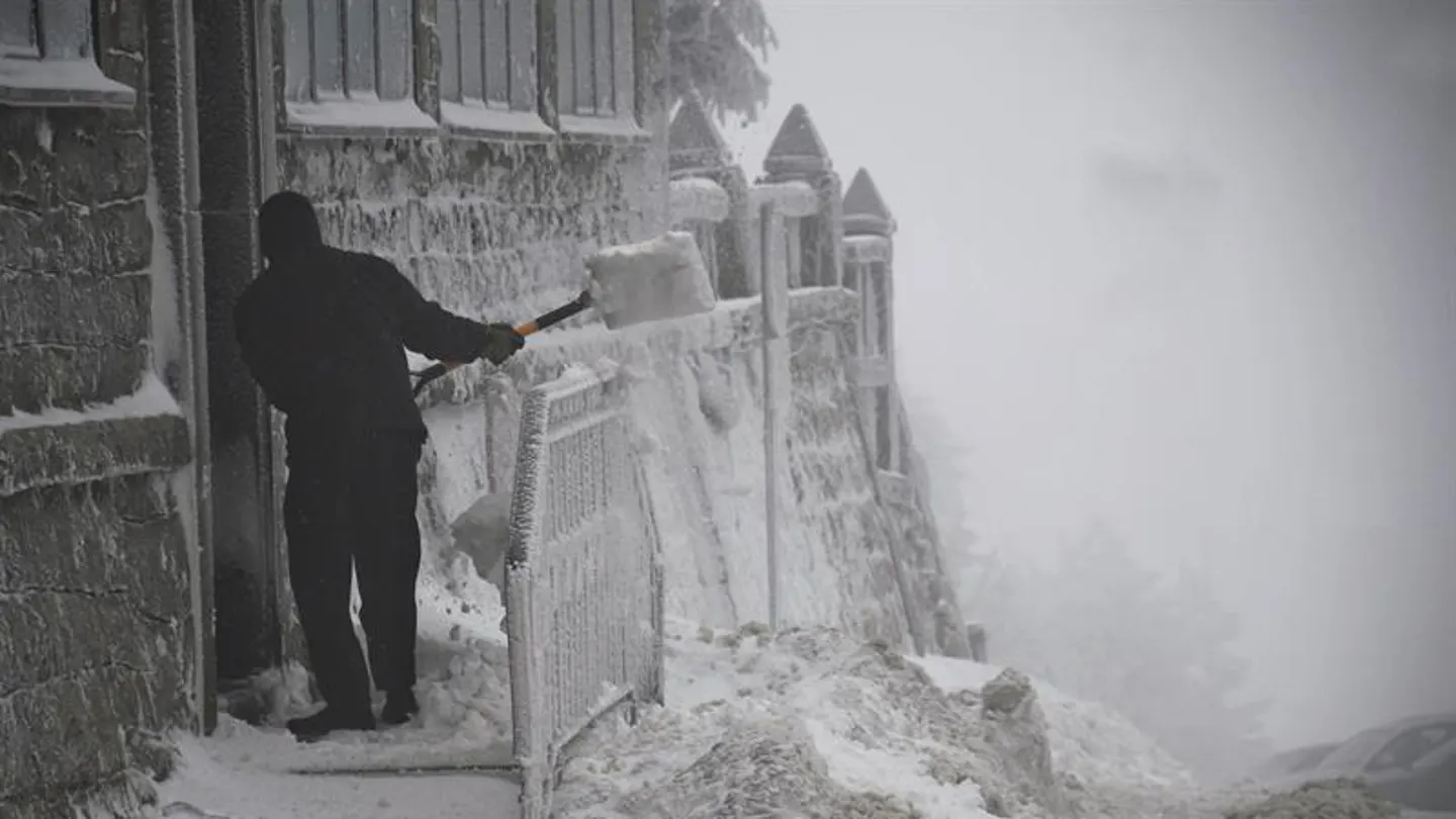 Un hombre retira la nieve de la puerta de una vivienda Un hombre retira la nieve de la puerta de una vivienda