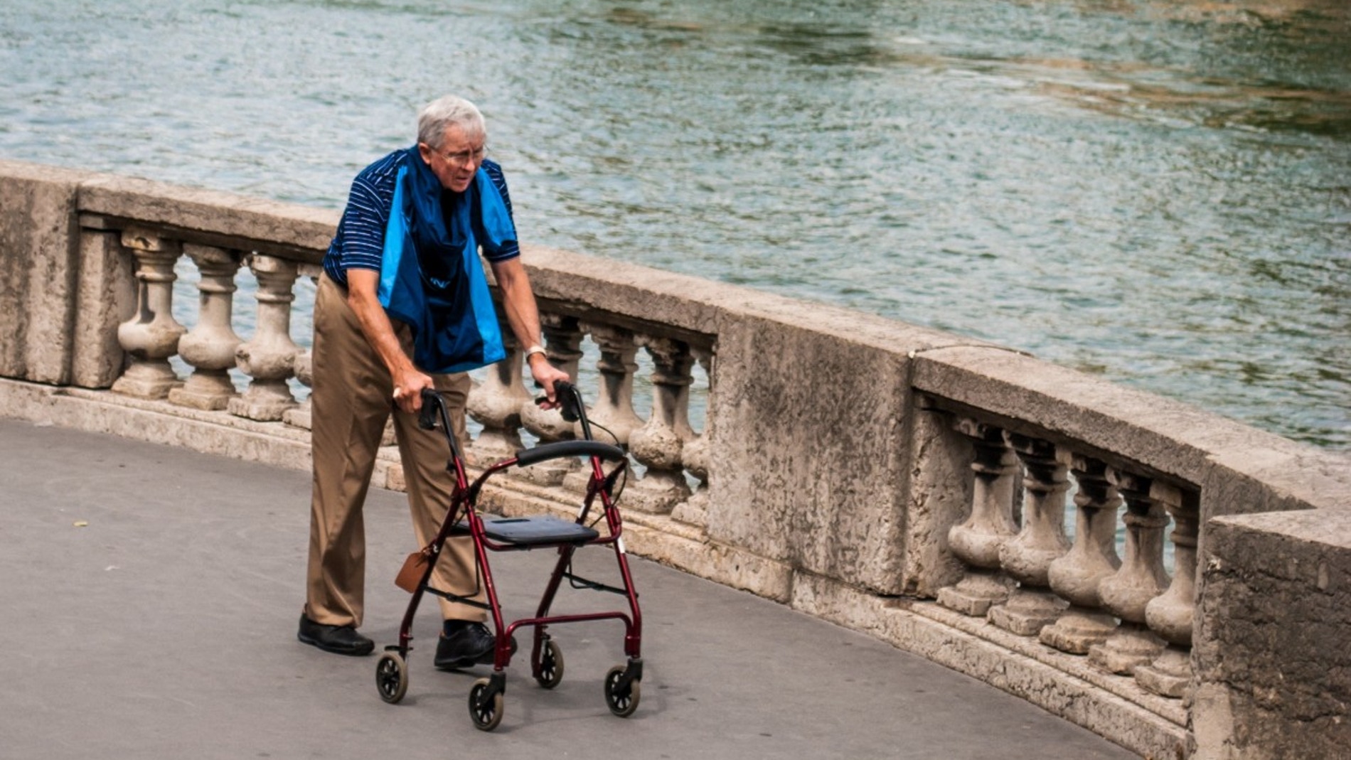 Un hombre camina con una ayuda junto al río Sena