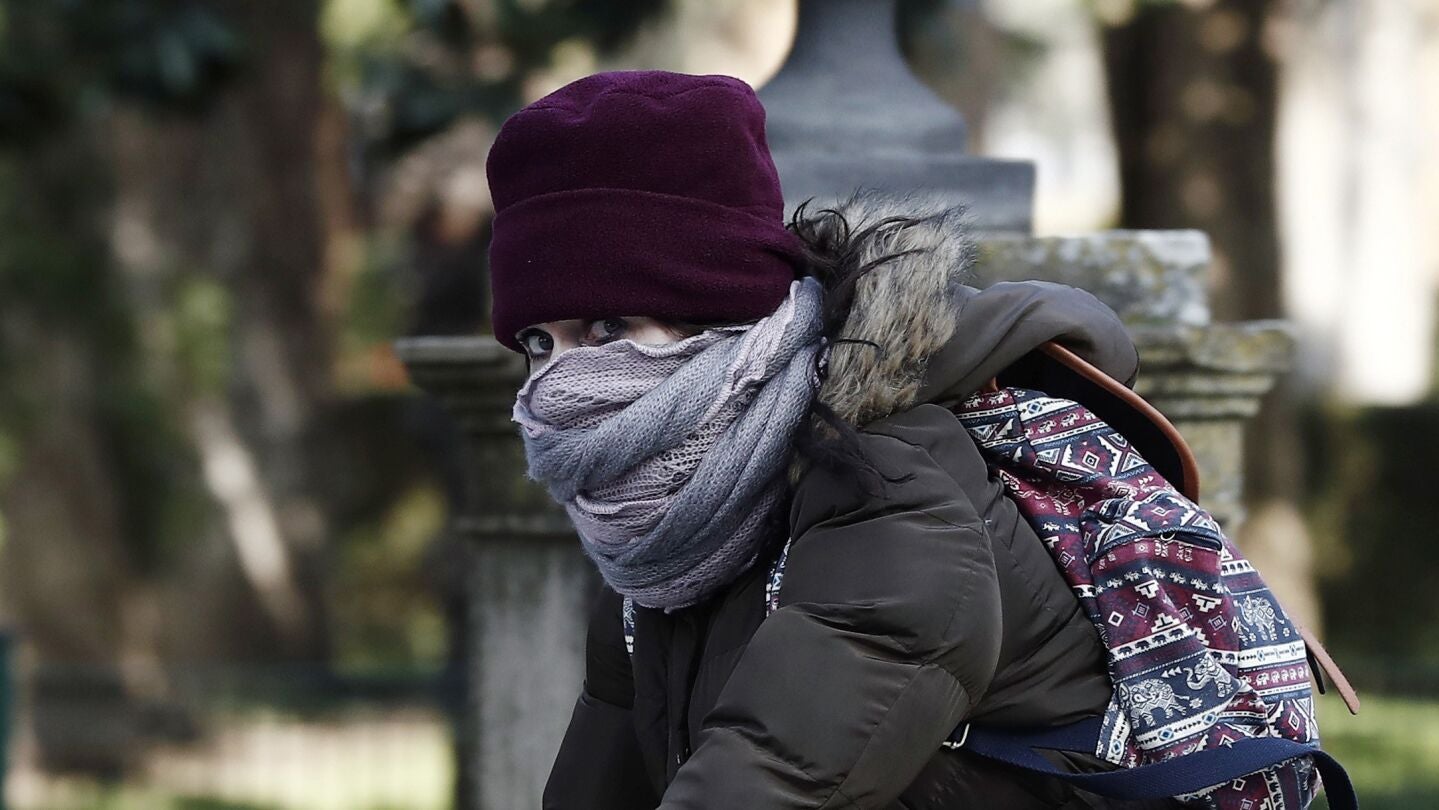 Una joven montada en su bicicleta se protege del fr&iacute;o 