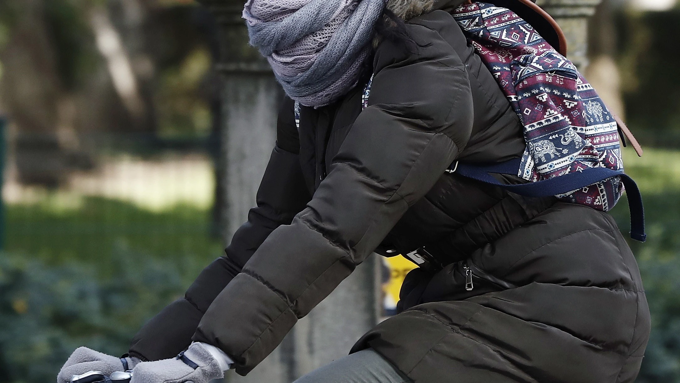 Una joven montada en su bicicleta se protege del frío 