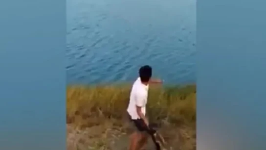 Imagen del joven lanzando al animal al agua Imagen del joven lanzando al animal al agua
