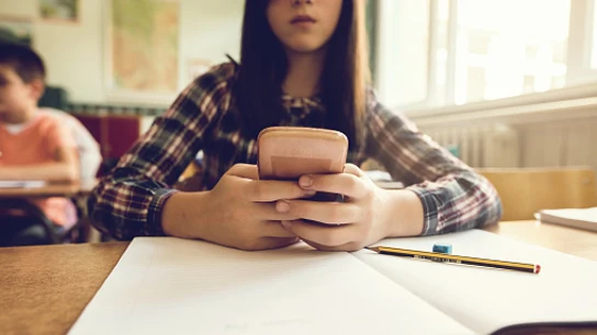 Una adolescente mira su móvil en clase Una adolescente mira su móvil en clase