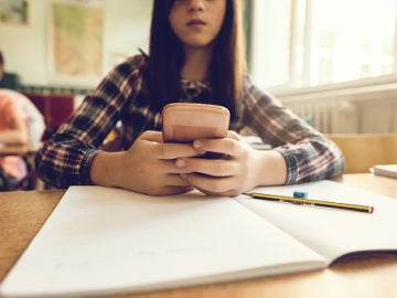 Una adolescente mira su móvil en clase Una adolescente mira su móvil en clase