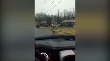 Un padre hace que su hijo vaya corriendo al colegio bajo la lluvia