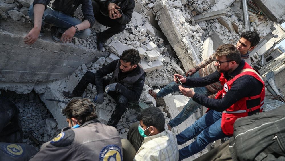 Miembros de Defensa Civil Siria mientras buscan el cuerpo de una víctima