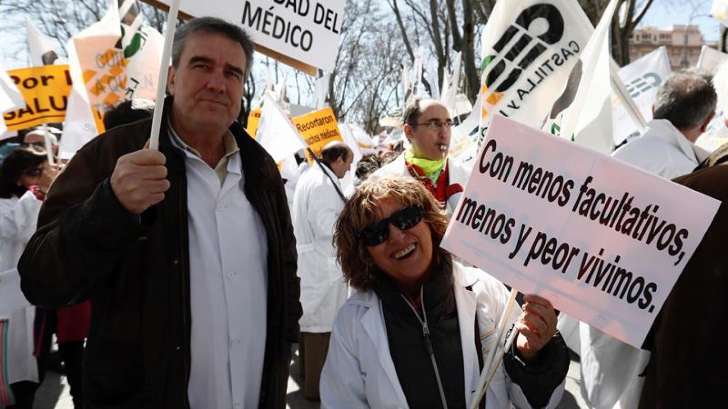  Dos m&eacute;dicos portan pancartas durante la manifestaci&oacute;n convocada por el colectivo hoy a las puertas del Ministerio de Sanidad 