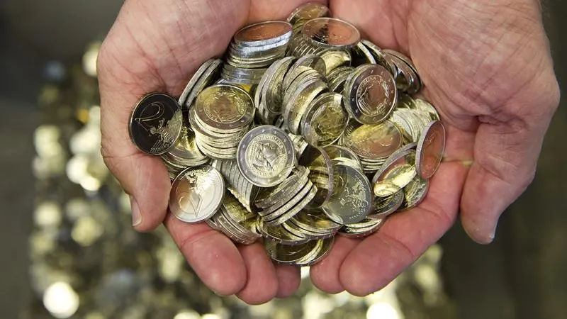 Un hombre sostiene varias monedas de euro