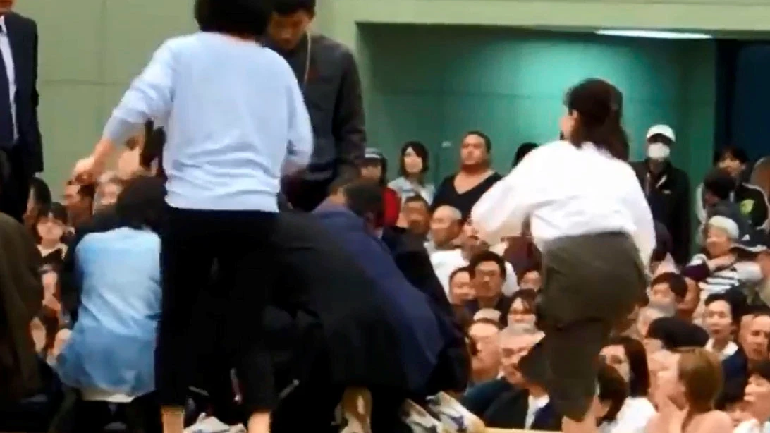 Varias mujeres tratan de reanimar a un hombre desfallecido en un ring de sumo Varias mujeres tratan de reanimar a un hombre desfallecido en un ring de sumo