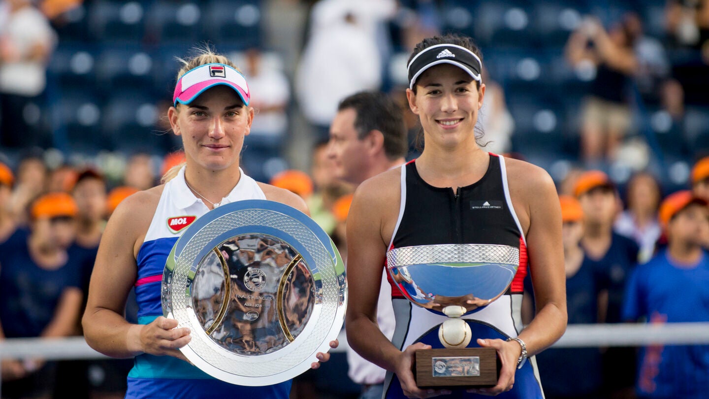 Garbi&ntilde;e Muguruza sostiene su trofeo de campeona junto a Babos