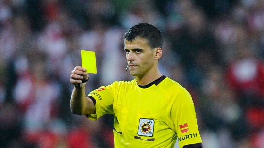 Gil Manzano muestra una tarjeta amarilla durante un partido