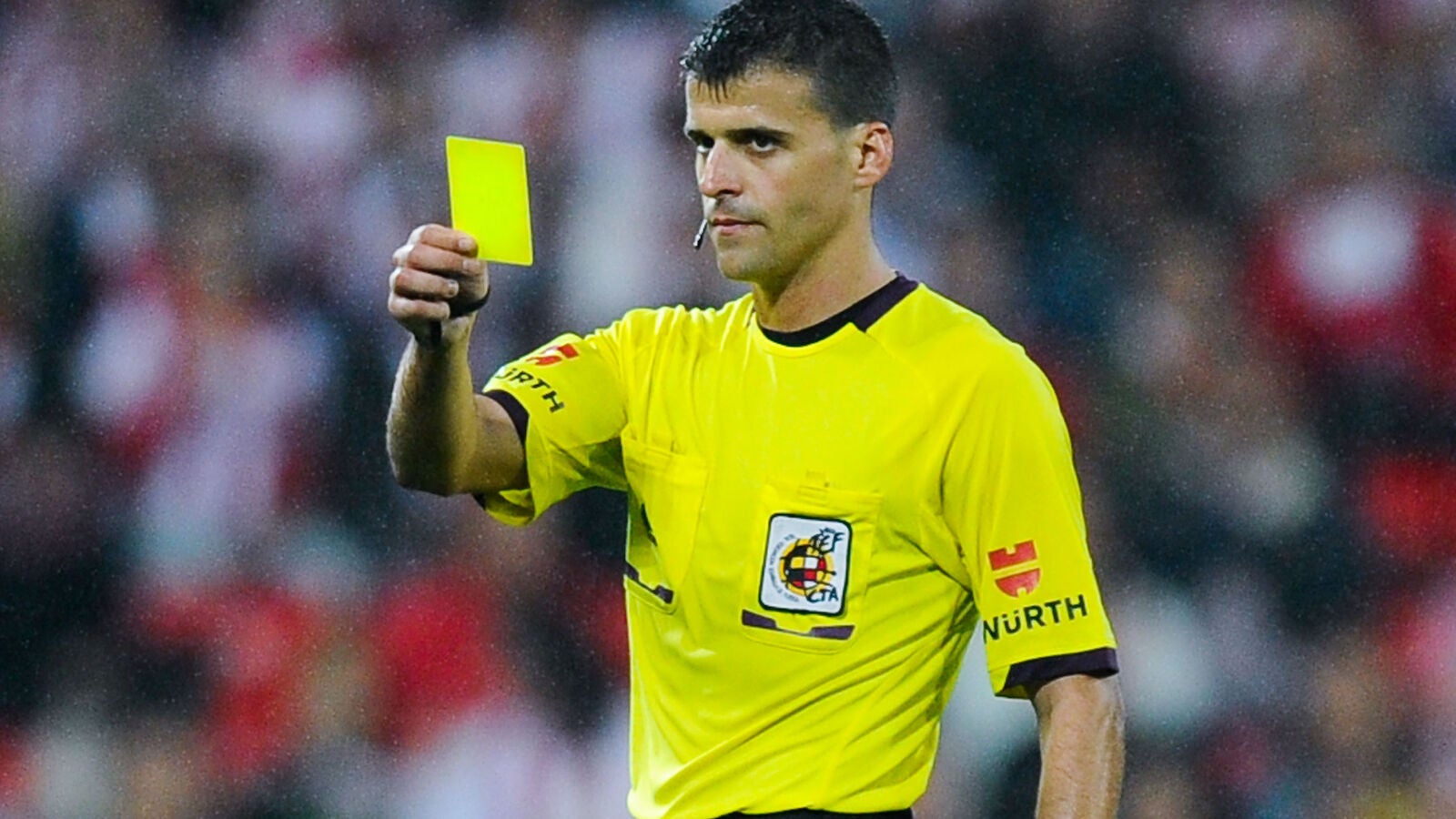 Gil Manzano muestra una tarjeta amarilla durante un partido