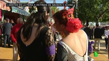 Dos mujeres portan un brazalete morado en la Feria de Abril