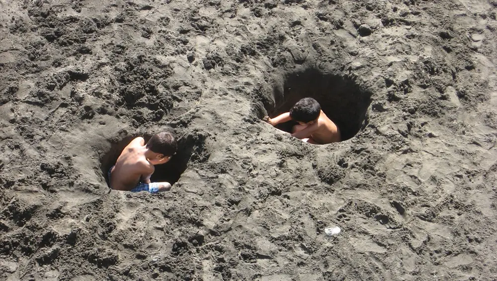 Niños cavando un agujero en la arena Niños cavando un agujero en la arena