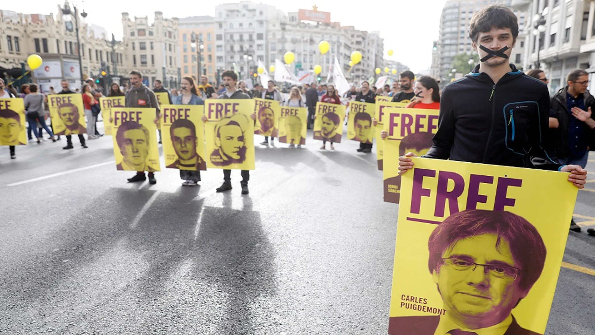 Varios jóvenes con las bocas precintadas llevan pancartas de los diputados catalanes investigados por el porcés