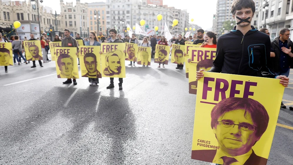 Varios jóvenes con las bocas precintadas llevan pancartas de los diputados catalanes investigados por el porcés