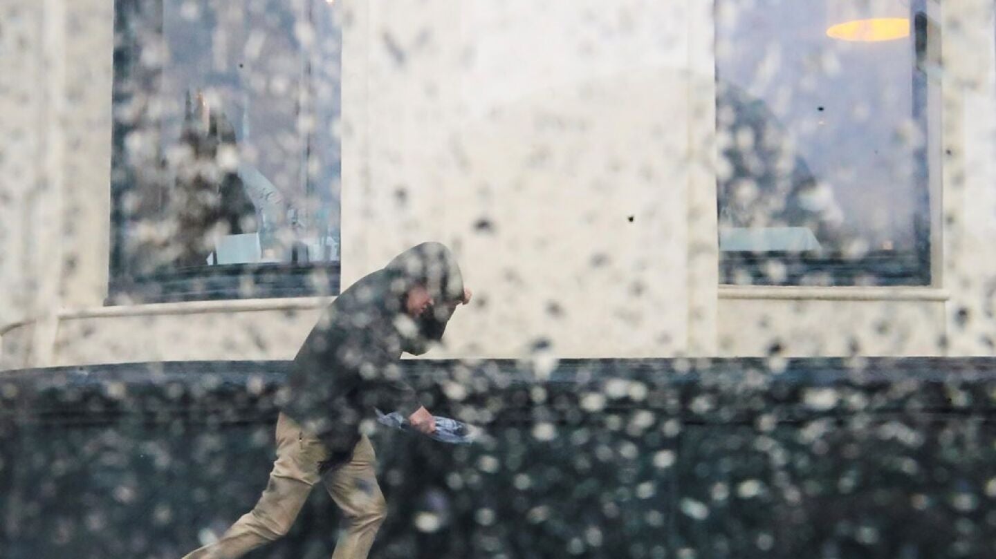 Imagen de archivo de un hombre intentando resguardarse de una tormenta
